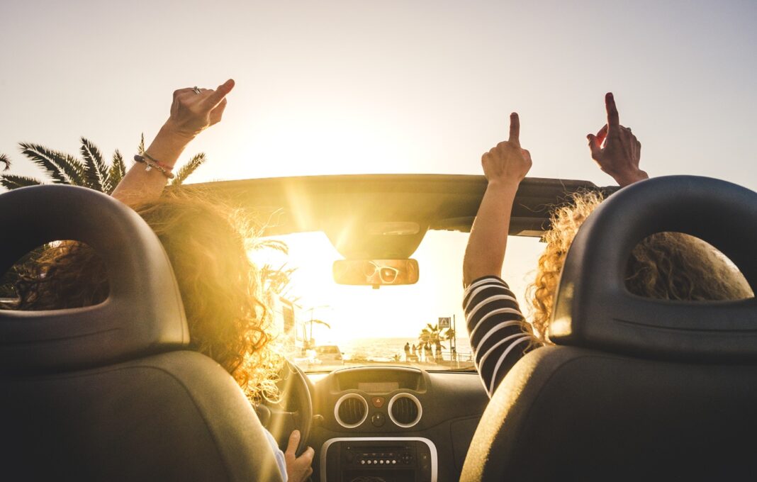 Couple of woman friends traveling and driving having a lot of fu